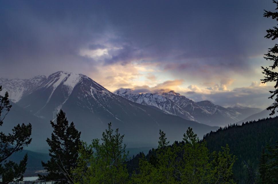 Free Image of Snow-covered mountains at dawn with colorful sky and trees 