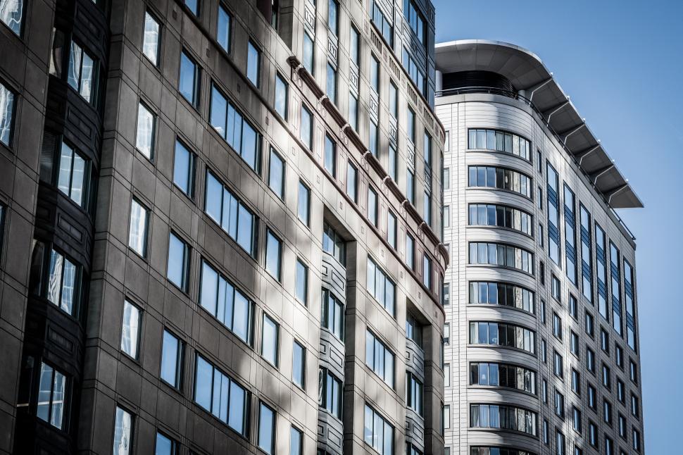 Free Image of Tall, modern buildings with glass windows under bright blue sky. 