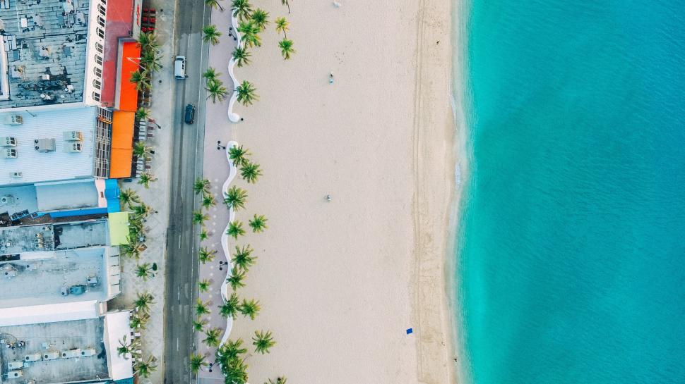 Free Image of Aerial view of tropical beach with clear waters and nearby structures. 
