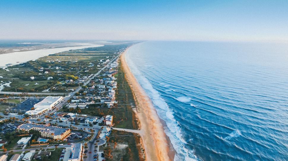 Free Image of Panoramic aerial view of a long coastal town with expansive beach. 