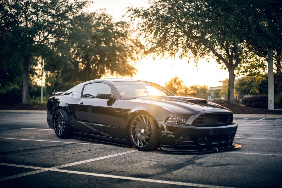 Free Image of A black sports car parked in a lot during a golden hour sunset. 