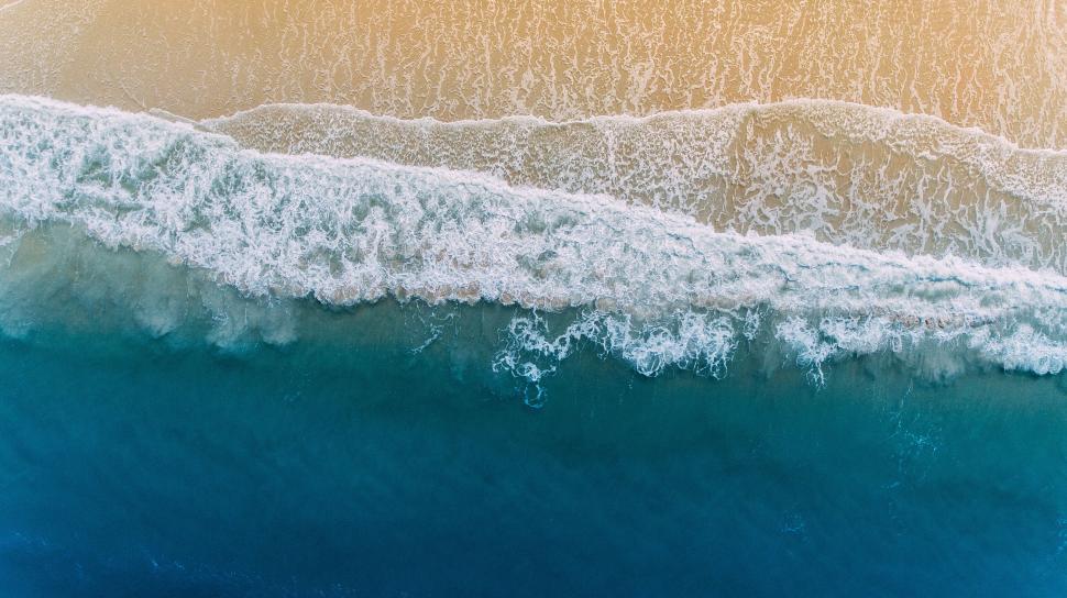Free Image of Aerial view of breaking ocean waves and golden sandy beach 