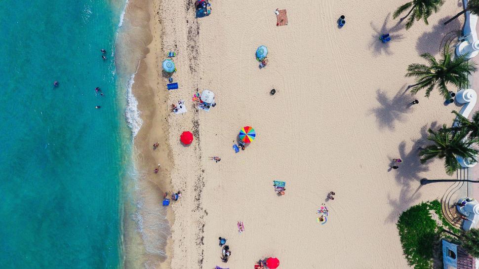 Free Image of Aerial image of people on a sandy beach with a turquoise ocean 