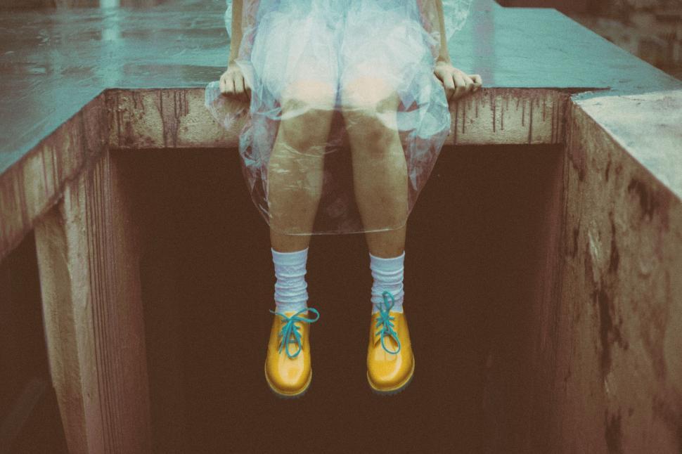 Free Image of Yellow boots and white socks on a child sitting on concrete edge 