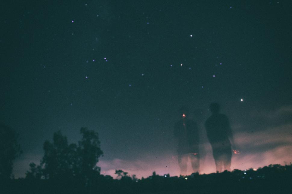 Free Image of Ghostly figures under a starry night sky in an eerie landscape. 