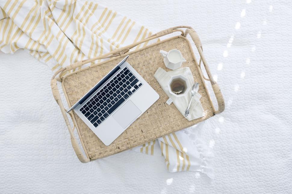 Free Image of Wicker tray on bed holding laptop and tea with white linens 