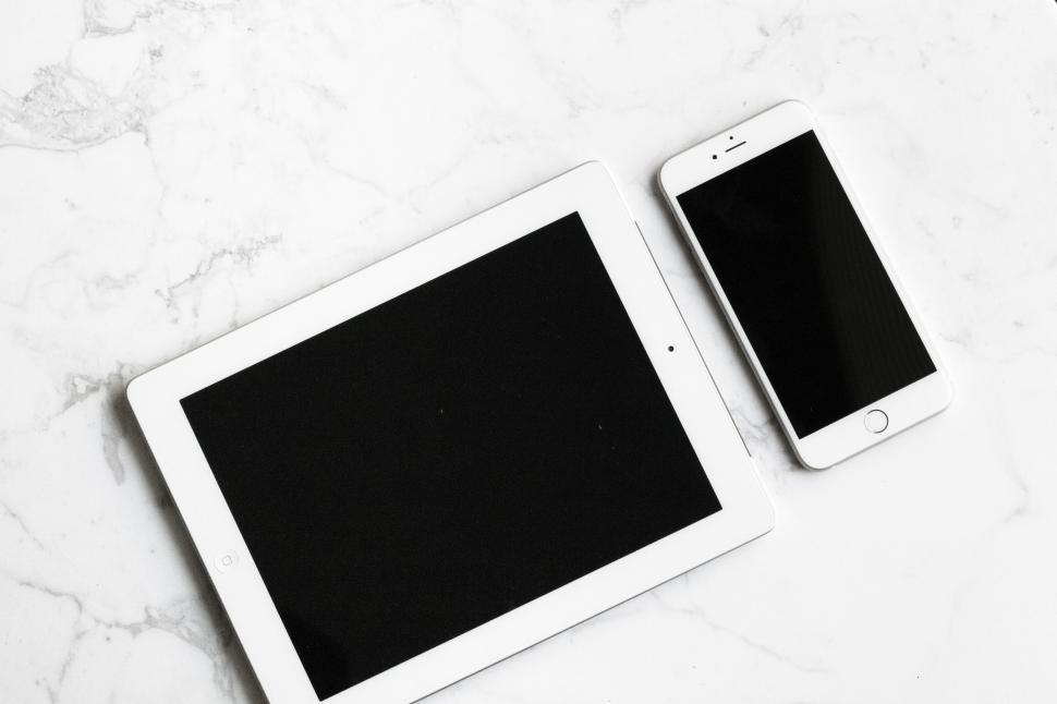 Free Image of White tablet and smartphone on a marble surface in bright light. 