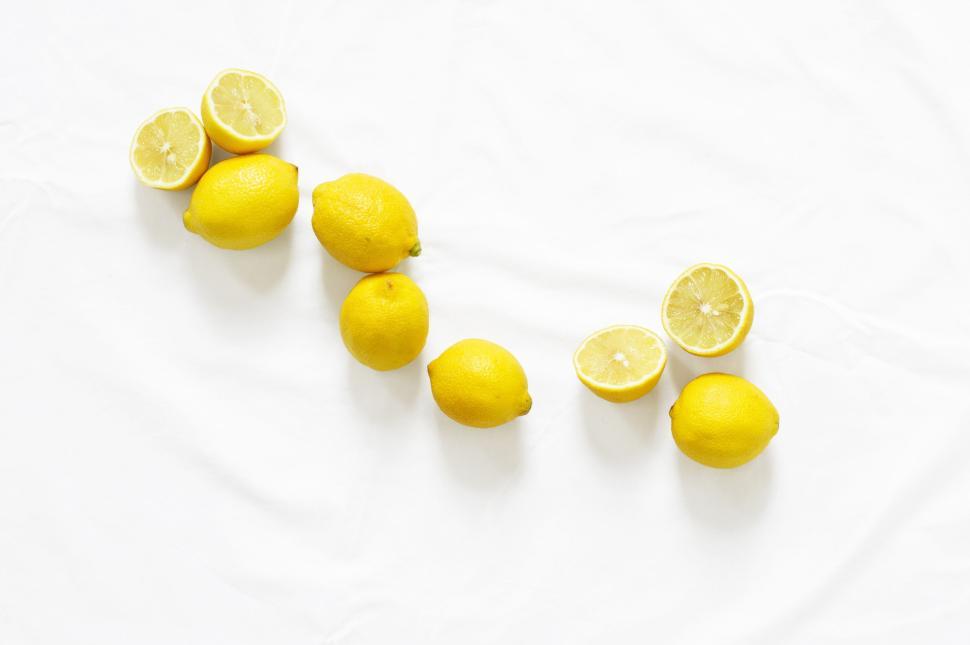 Free Image of Bright yellow lemons scattered on a white surface in natural light. 