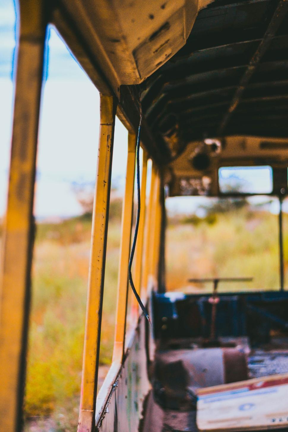 Free Image of Inside view of an abandoned yellow bus with broken windows and seats. 