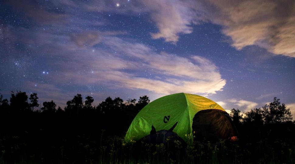 Free Image of Green tent under a starry night sky in an open field with flowers. 