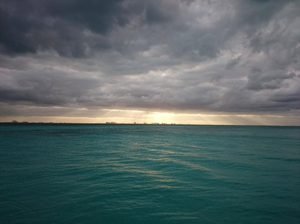 Free Image of Calm turquoise sea under a cloudy sky with distant horizon view. 