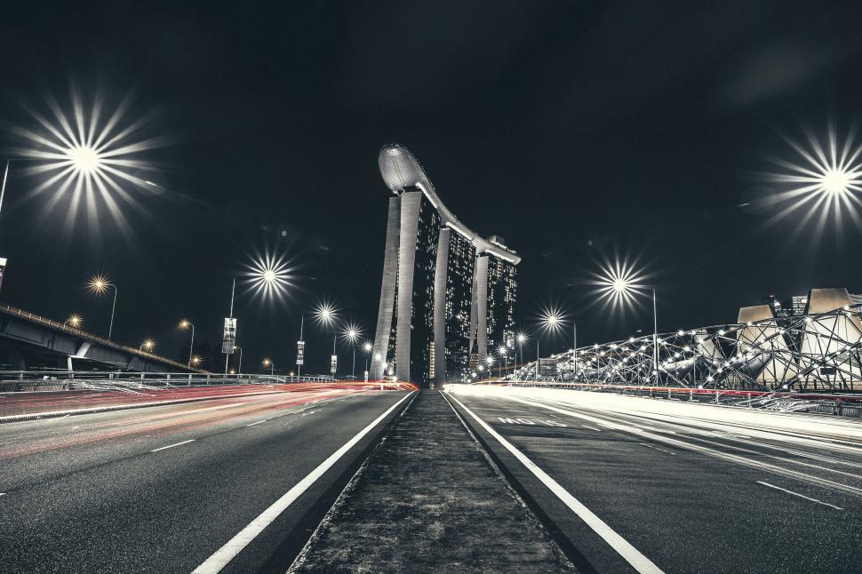 Free Image of Light trails on the bridge leading to Marina Bay Sands at night. 