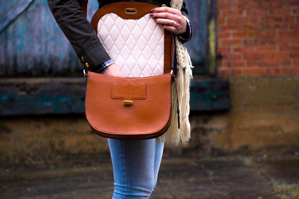 Free Image of Stylish woman opening brown leather bag with quilted interior 