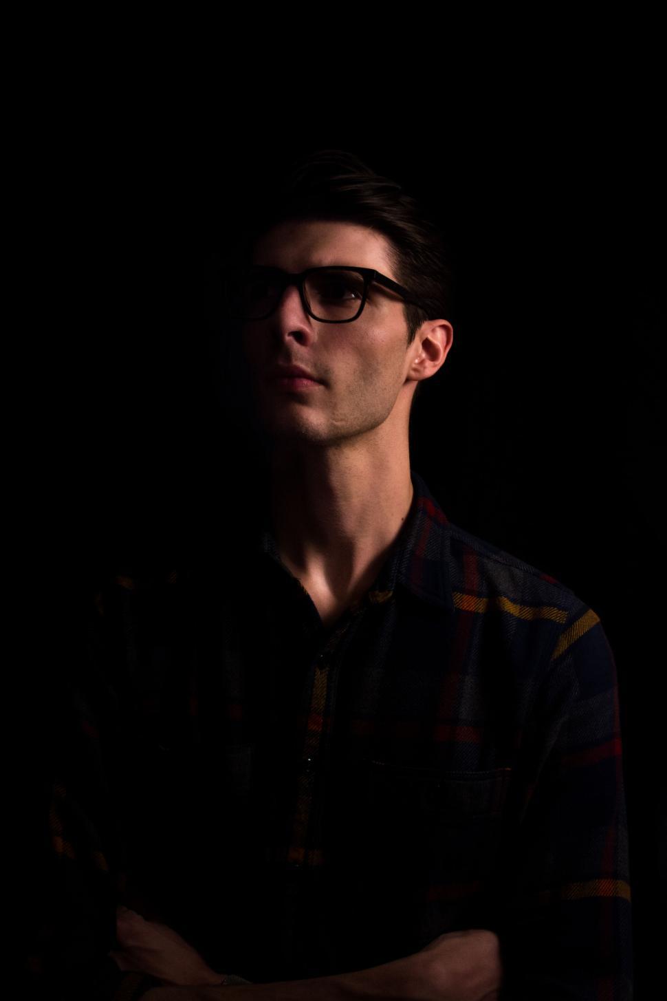 Free Image of Mystery portrait of person in plaid shirt against dark background 