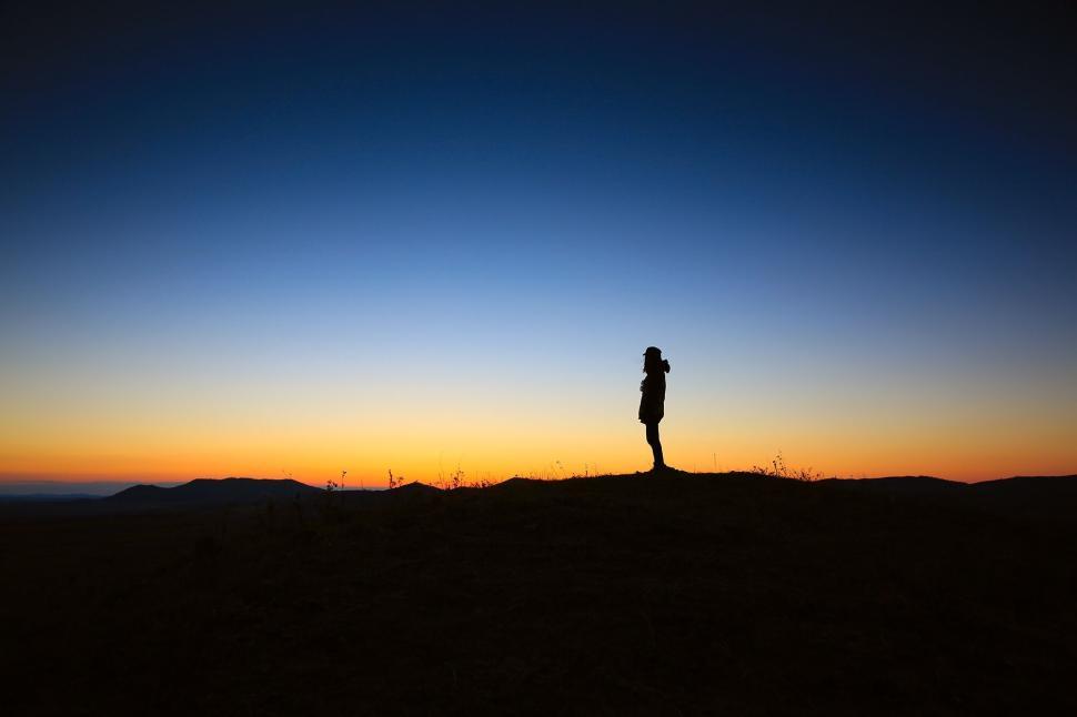 Free Image of Silhouette of person standing against vibrant sunset landscape 