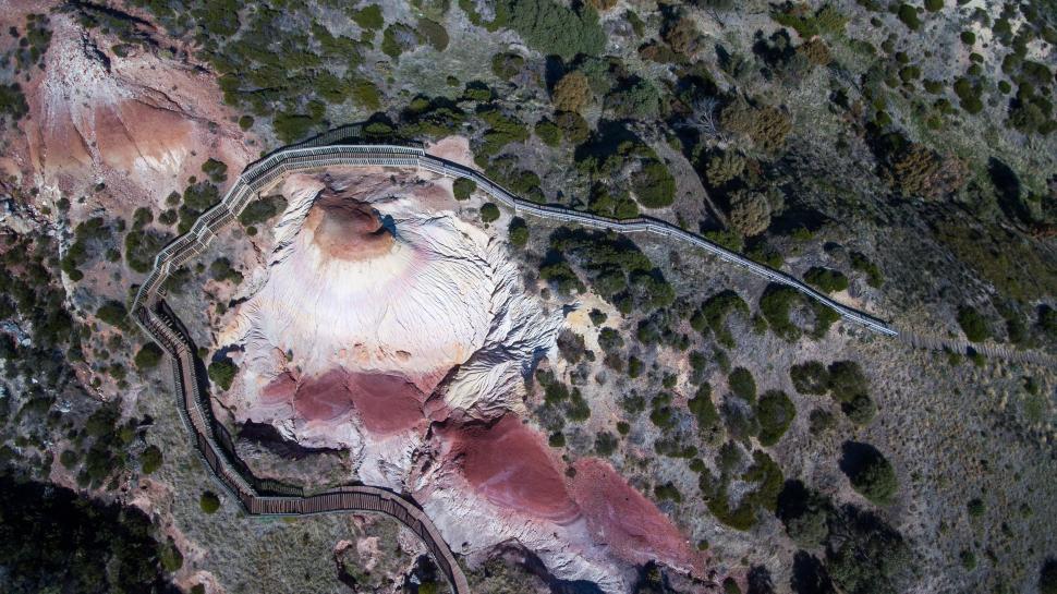 Free Image of Aerial view of rugged terrain with colorful erosion and pathway 