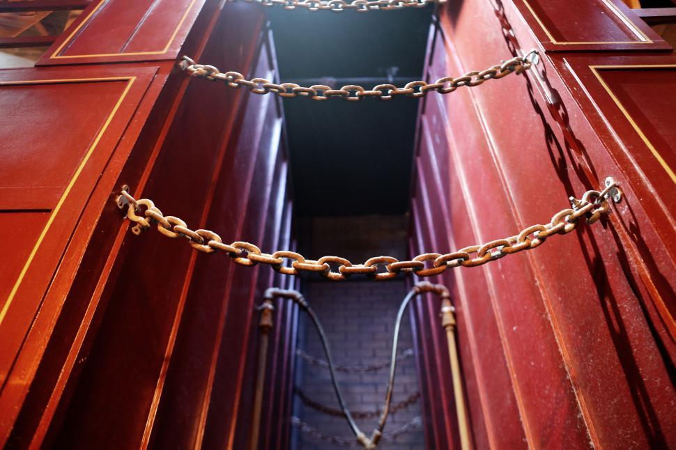 Free Image of Chains hanging between red panels in symmetrical indoor industrial setup 