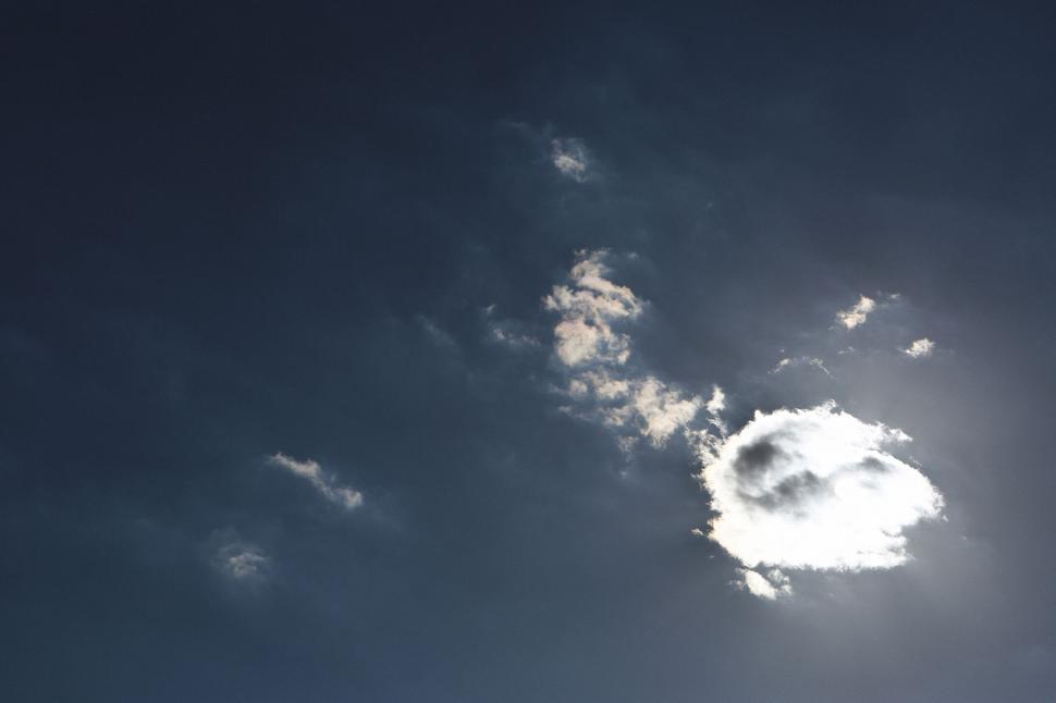 Free Image of Bright sun partially obscured by fluffy clouds in a blue sky. 