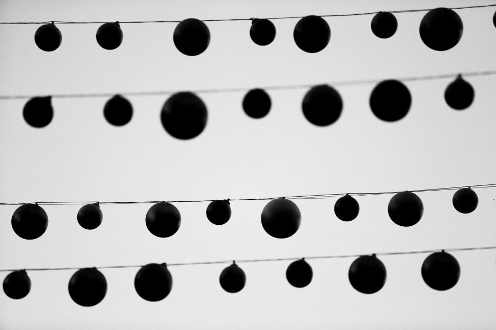 Free Image of Strings of round decorative lights hanging in a pattern against sky. 