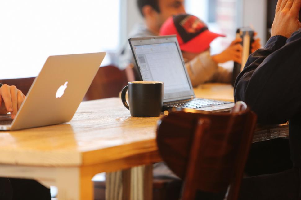 Free Image of Casual work setup at cafe with laptops, coffee, and wooden table. 