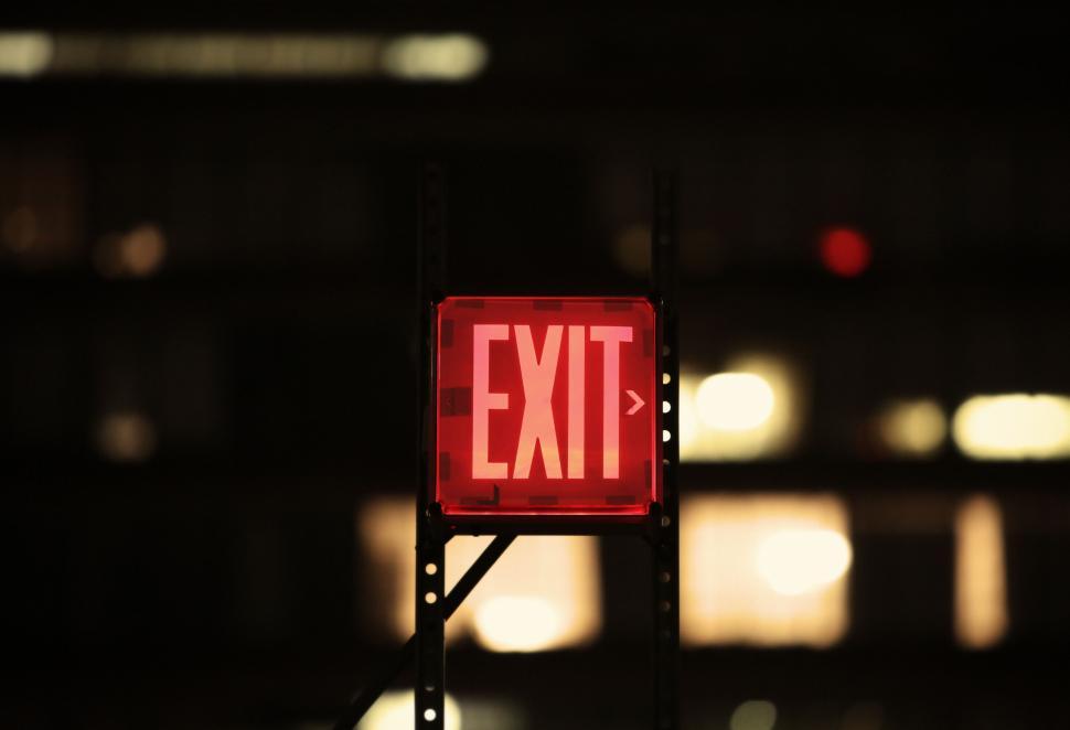 Free Image of Red exit sign illuminated against a dark urban background. 