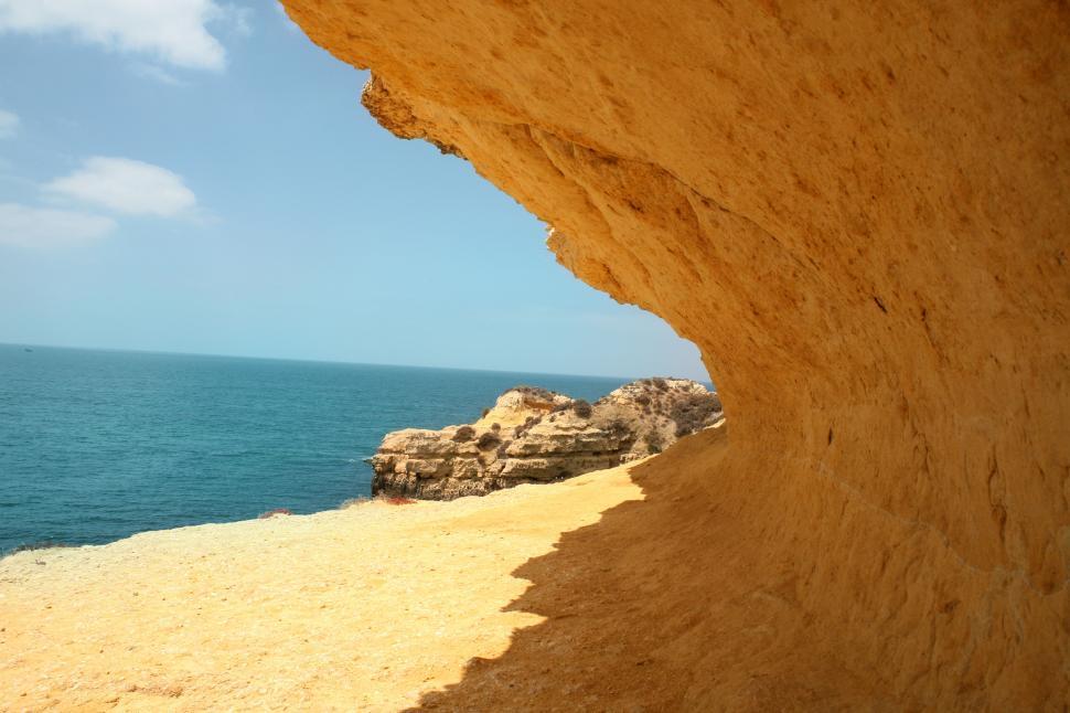 Free Image of Scenic rocky cliffside with ocean view under a clear blue sky 