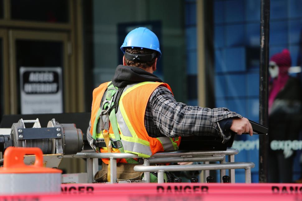 Free Image of Construction worker in safety gear operating machinery at a site. 