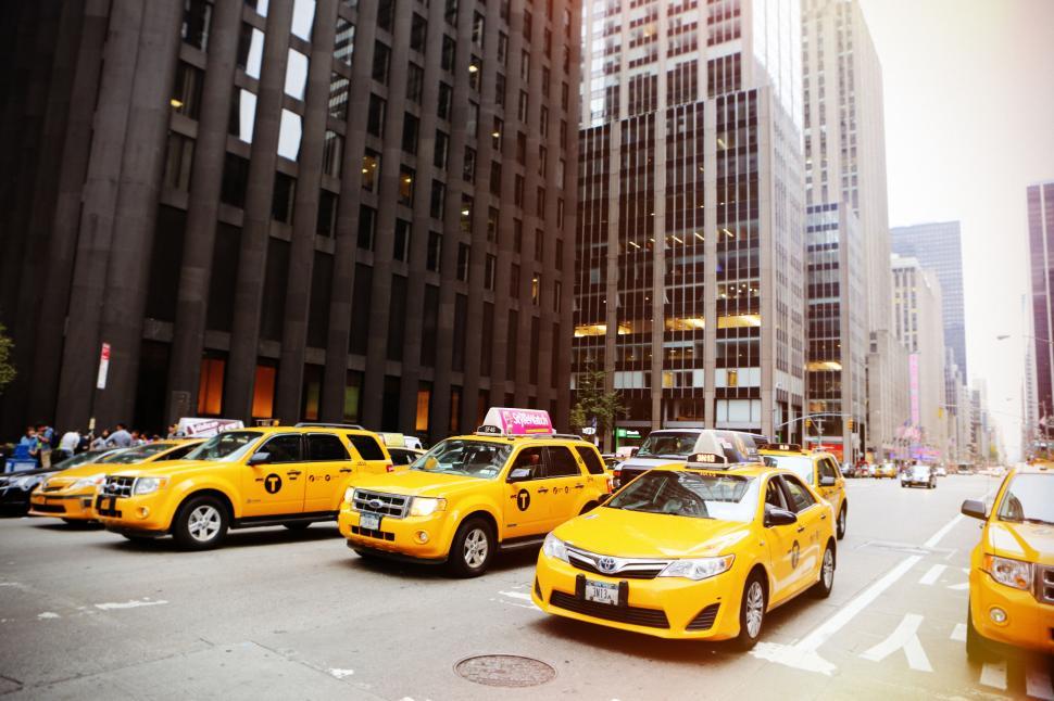 Free Image of Line of yellow taxis driving through the busy city streets, daytime. 