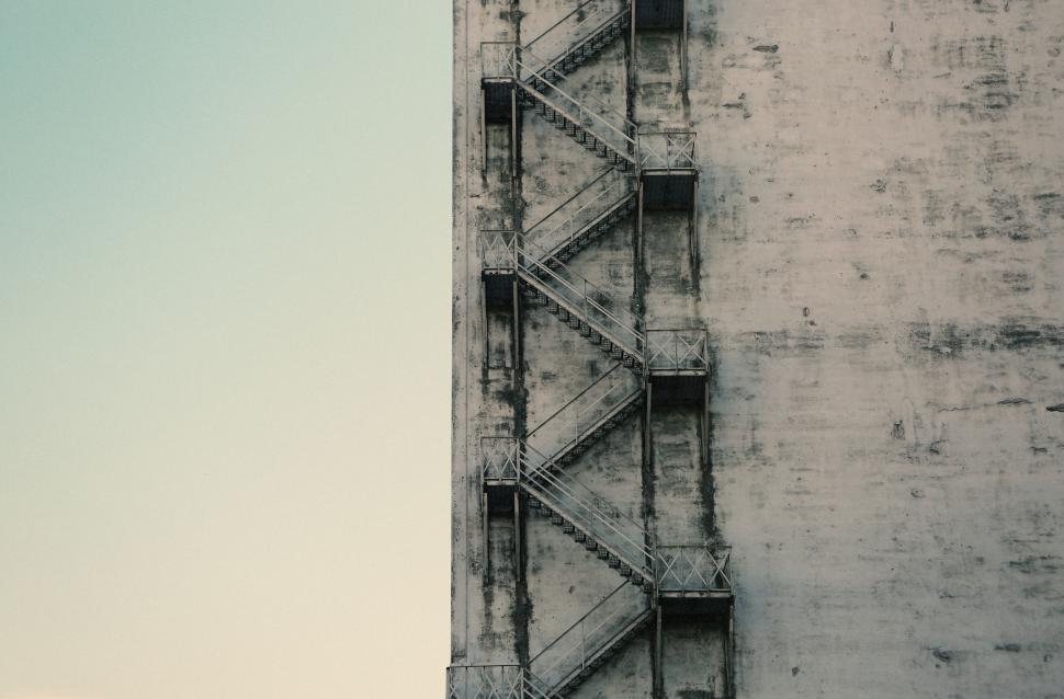Free Image of Concrete building with old fire escape stairs against clear sky 