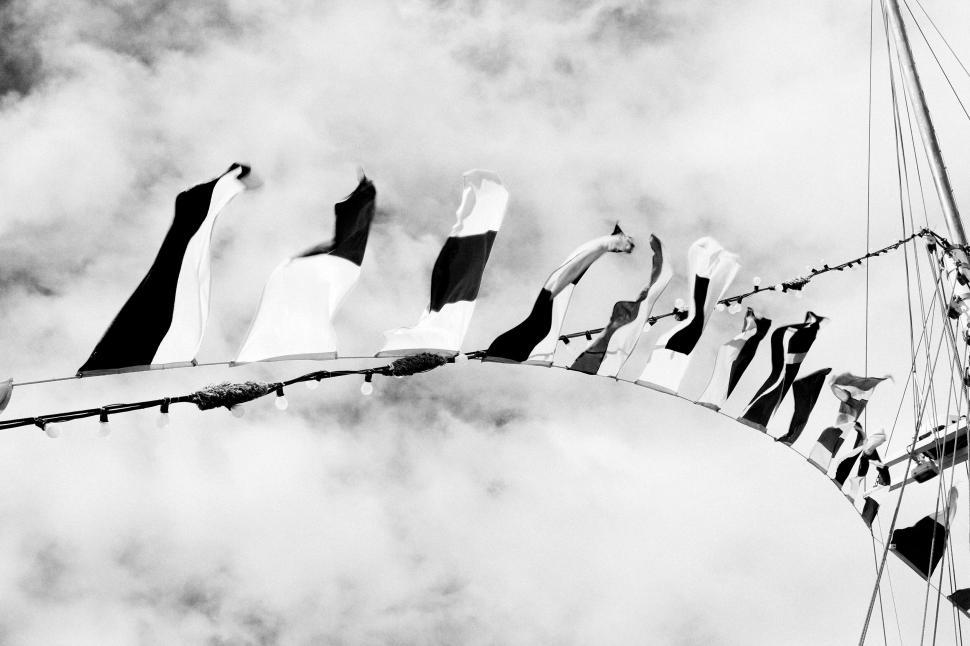 Free Image of Black and white photograph of flags waving under a cloudy sky 