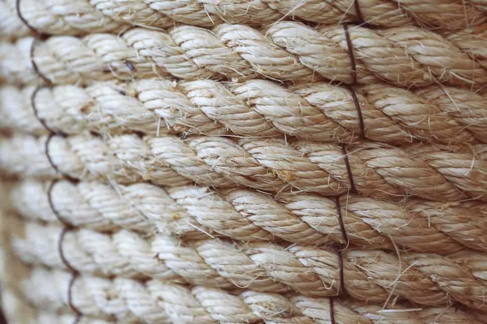 Free Image of Coiled beige rope with secure black tie on the side in close-up 
