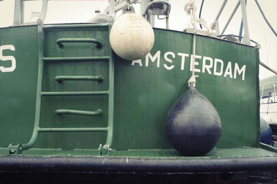 Free Image of Green boat with Amsterdam label and hanging white buoy 