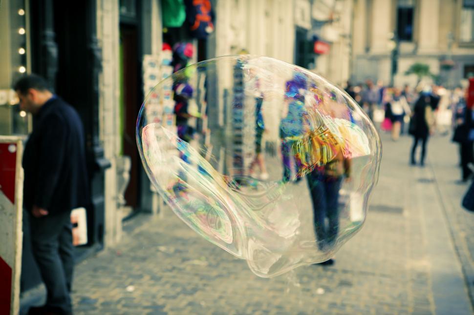 Free Image of Large soap bubble floating in busy city street filled with people 