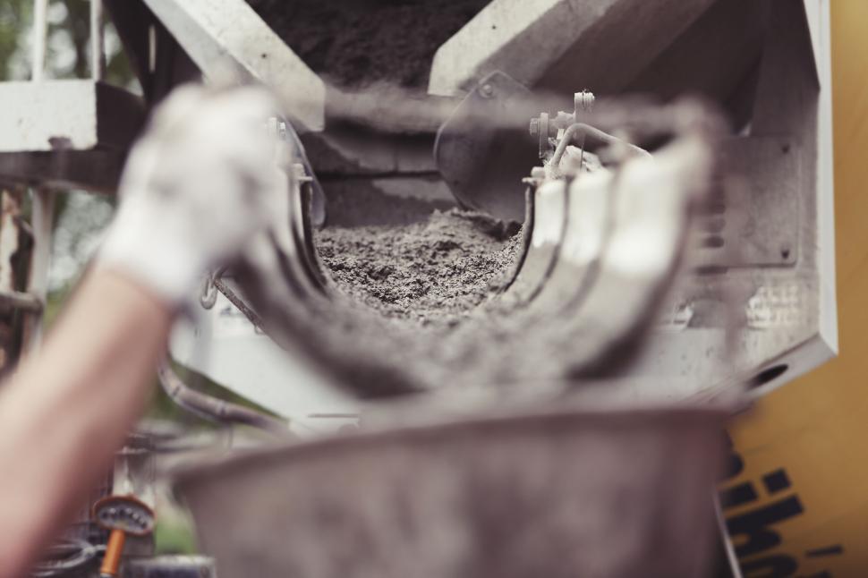 Free Image of Concrete being poured from a mixer into a container. 