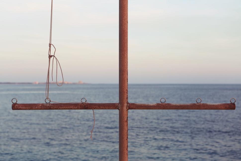 Free Image of Simple cross-shaped structure with ropes over a calm ocean scene 