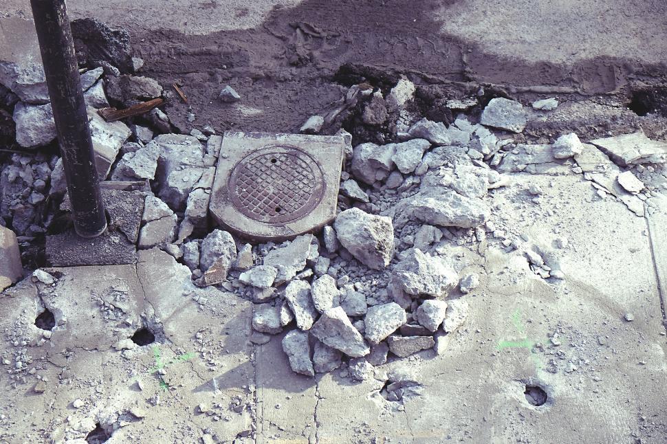 Free Image of Crumbled pavement and open manhole on a damaged city street 