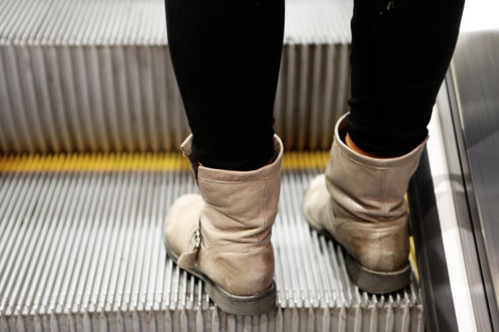 Free Image of Person with beige boots standing on the steps of an escalator. 