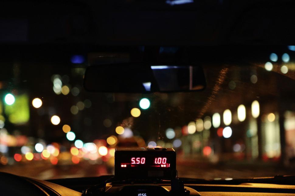 Free Image of Blurry city lights seen through car windshield with taxi meter display 