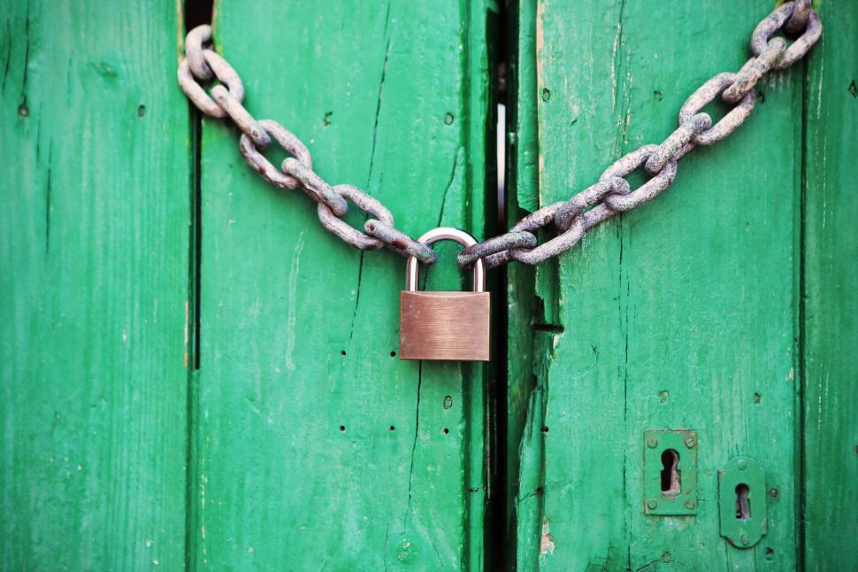 Free Image of Green wooden door secured by chain and padlock against entry. 