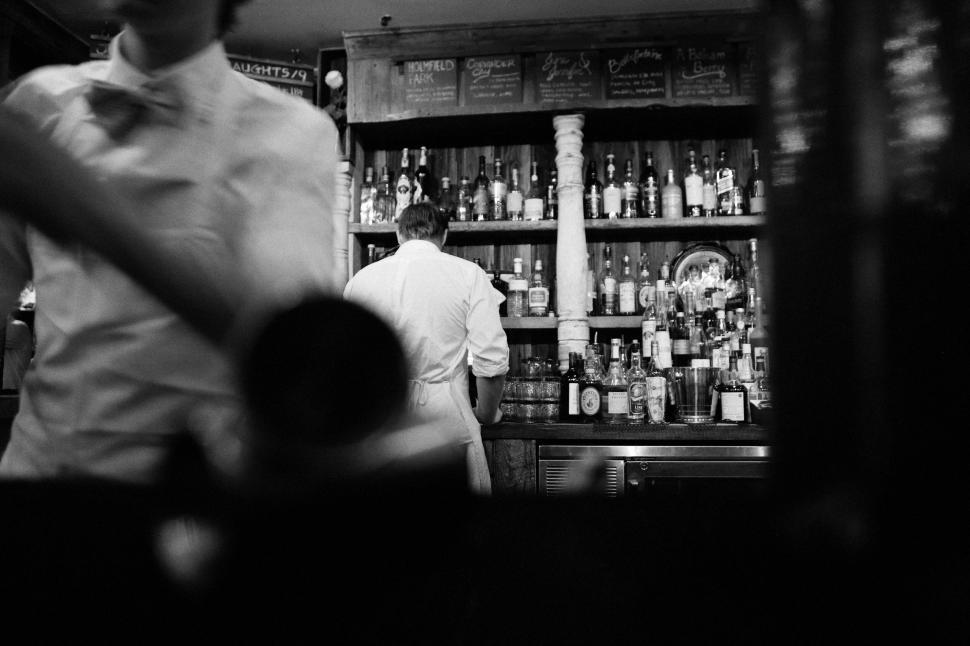 Free Image of Black and white photo of bartenders working in a vibrant bar. 