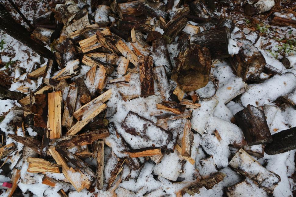 Free Image of Snow-covered pile of chopped firewood logs in a cold winter scene. 