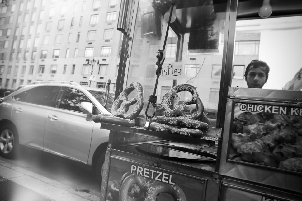 Free Image of Street vendor cart selling pretzels and chicken in a city setting. 