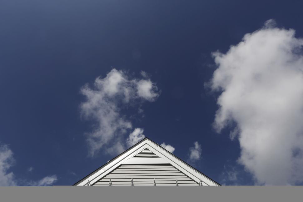 Free Image of White house gable with hooks against blue cloudy sky background. 