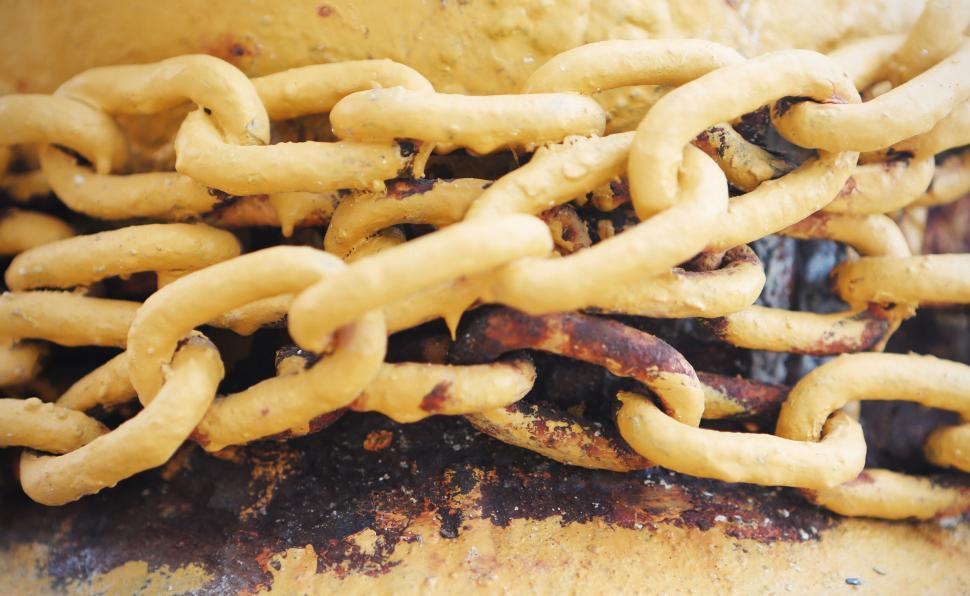 Free Image of Close-up of yellow rusted chains wrapped around weathered metal post. 