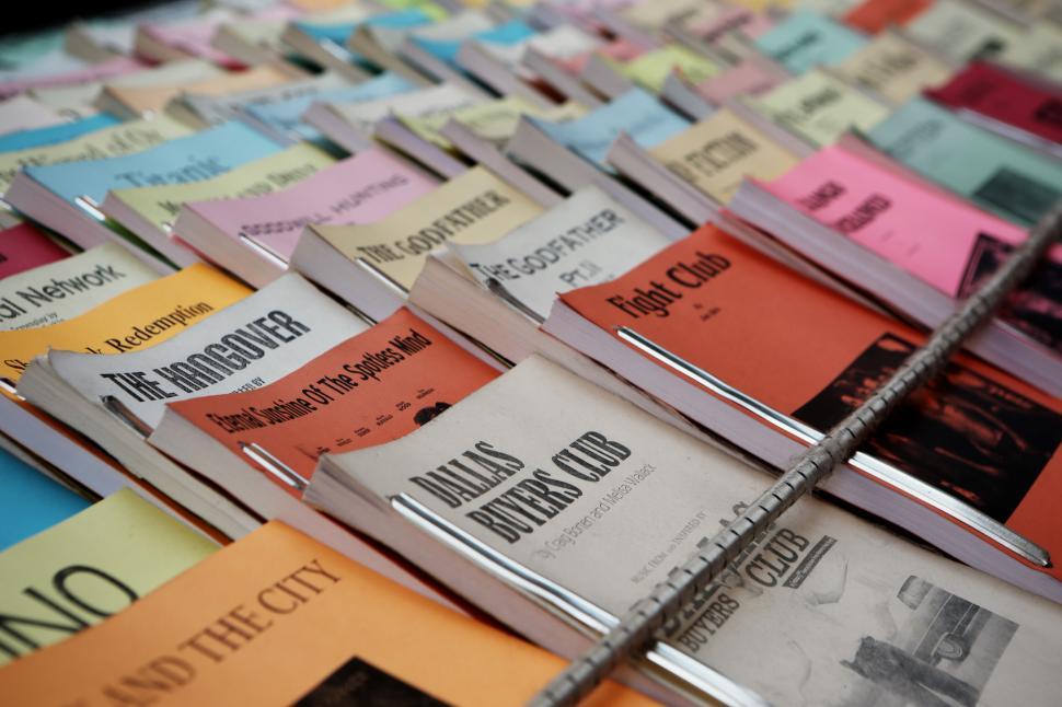 Free Image of Assorted colorful screenplays neatly arranged in rows on a table. 