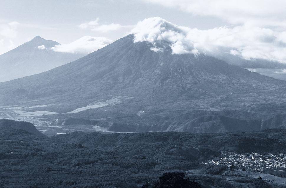Free Image of Two mountains partially covered by clouds under a bright sky. 