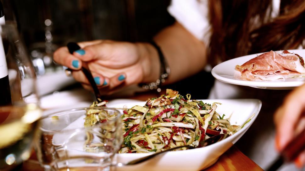 Free Image of Person Serving Fresh Salad in a Cozy Restaurant Setting 