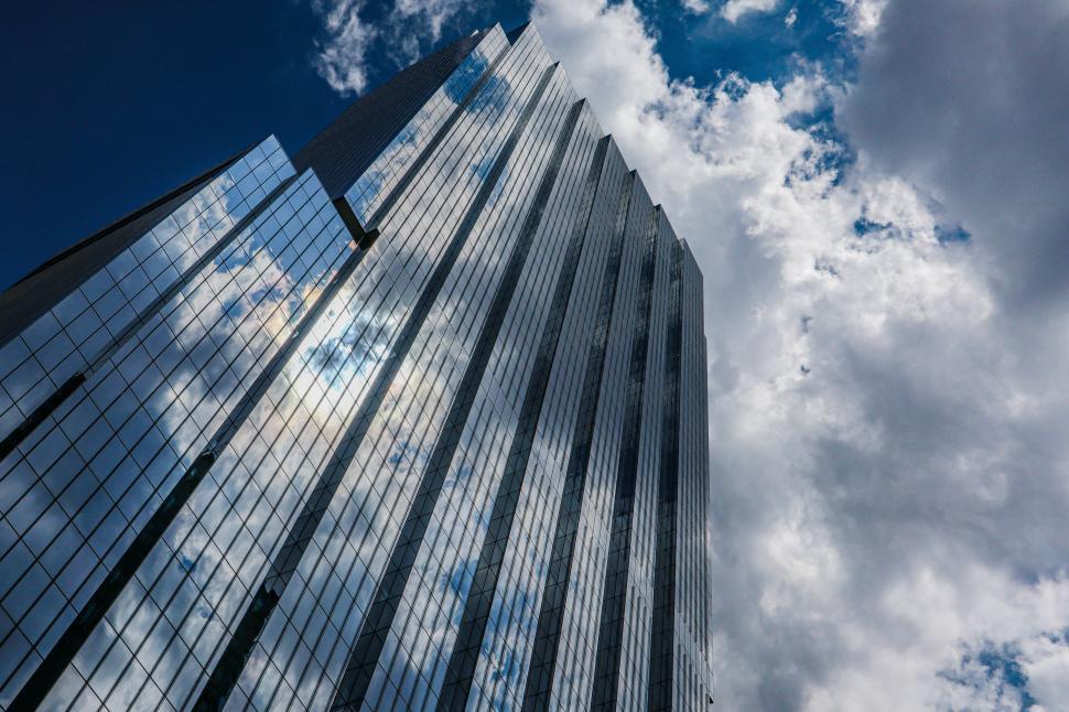 Free Image of Modern skyscraper reflecting clouds on a partly cloudy day. 