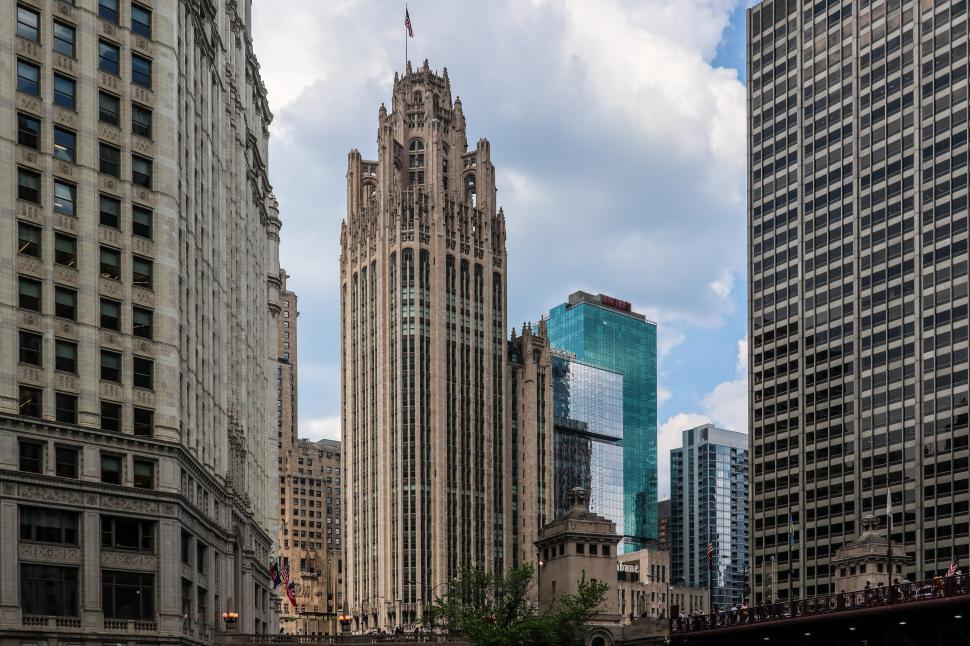 Free Image of Gothic Chicago Tribune Tower amidst modern buildings under scattered clouds. 