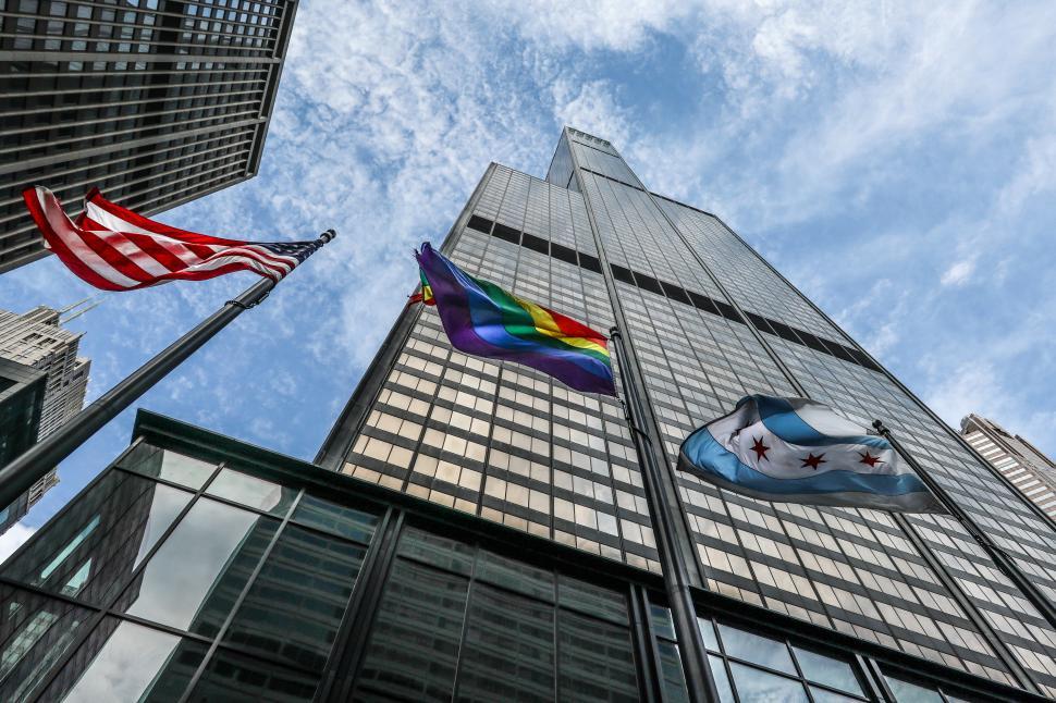 Free Image of Dramatic upward shot of Willis Tower with surrounding flags on windy day 